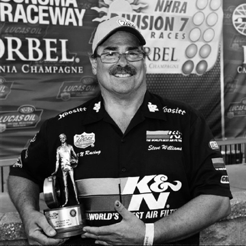 Steve Williams holding an NHRA trophy 